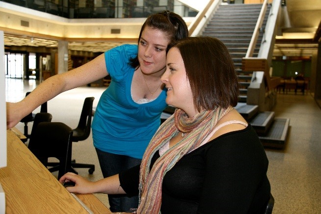 Lesa Holmes & Sarah Van Heulvelen work on a computer in Bata Library