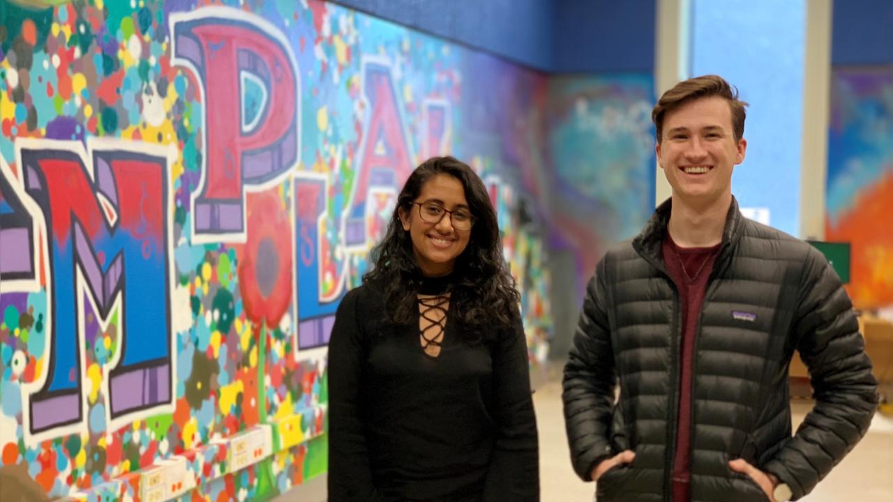 Two Champlain students in front of a wall of graffiti