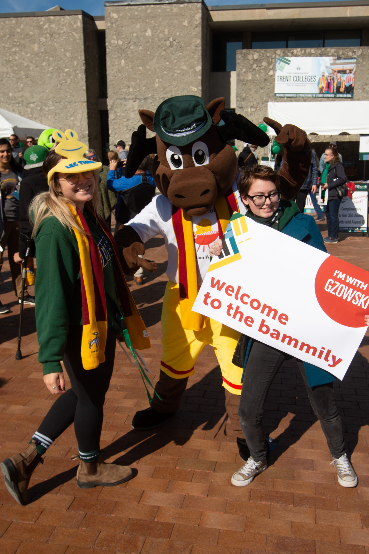 Bamm the moose at an event posing for a picture with two individuals