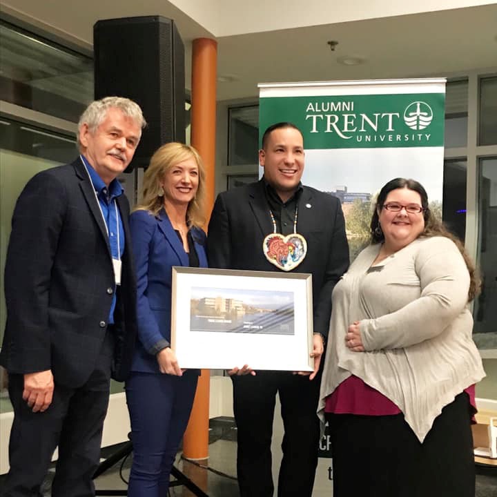 4 people holding an alumni award