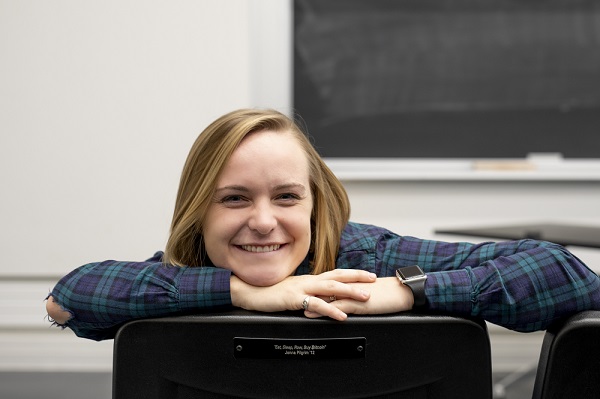 Jenna Pilgrim sitting in her Stohn Hall Seat that reads "Eat, Sleep, Row, Buy Bitcoin"